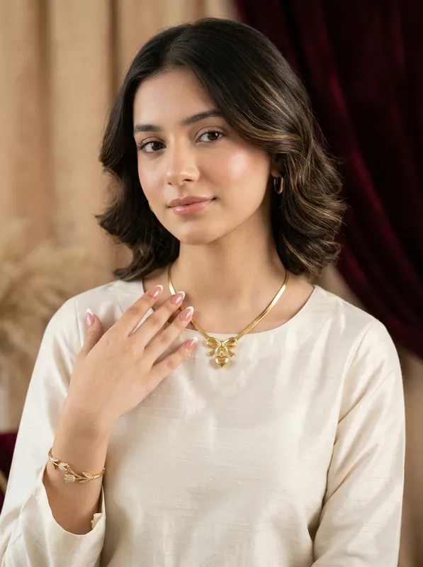 Model wearing 18k herringbone bow necklace, bracelet and nails